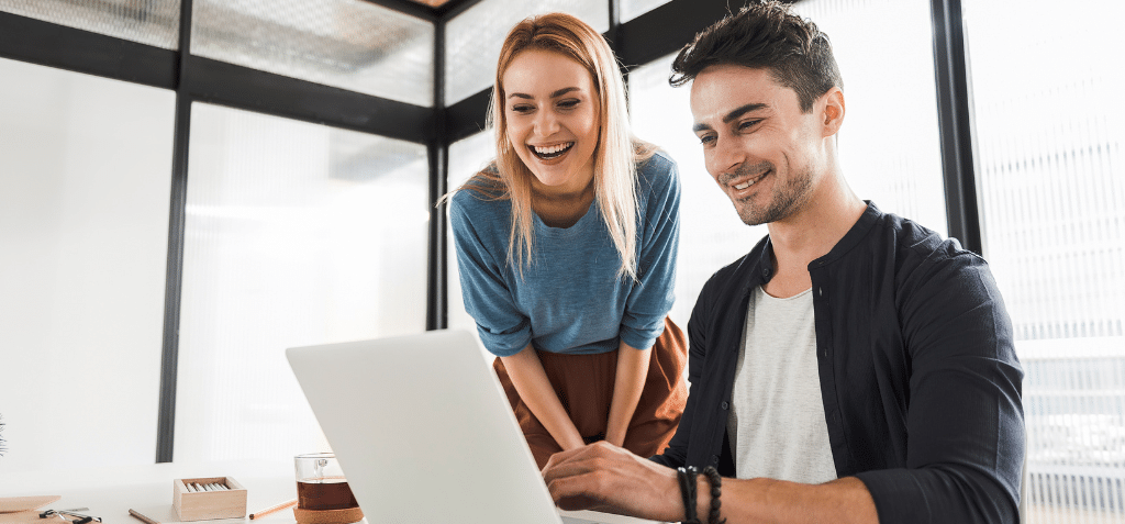 Two young office workers collaborating in front of a laptop