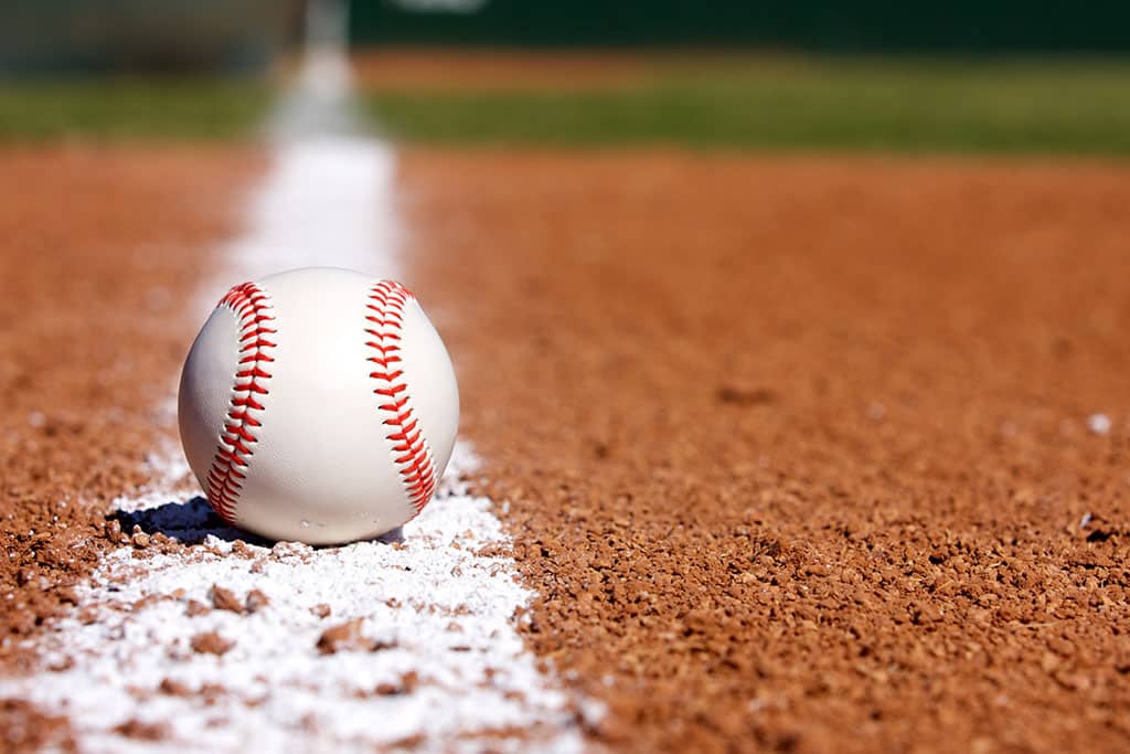 baseball sitting on the line in the dirt in the infield