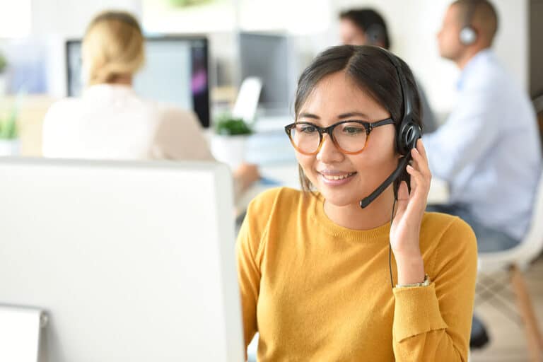 female technical support rep in a yellow sweater wearing a headset