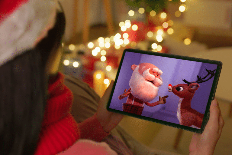 a woman in a santa hat watching a classic holiday special on a tablet