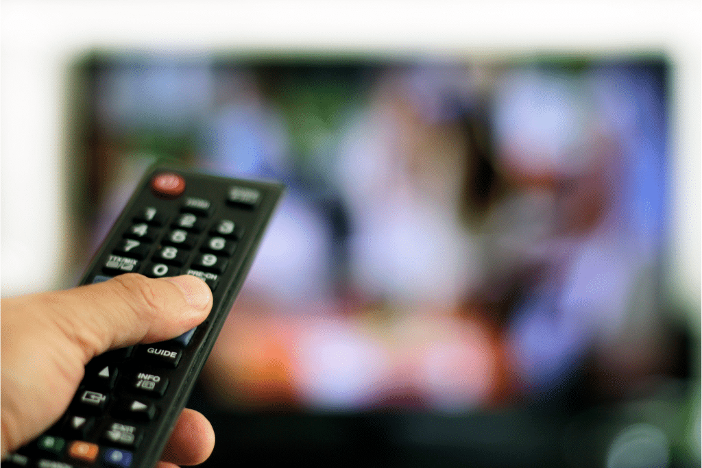 Hand with a TV remote in front of a television