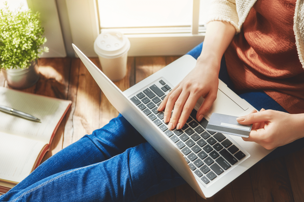 Laptop in a woman's lap, she's holding a credit card.