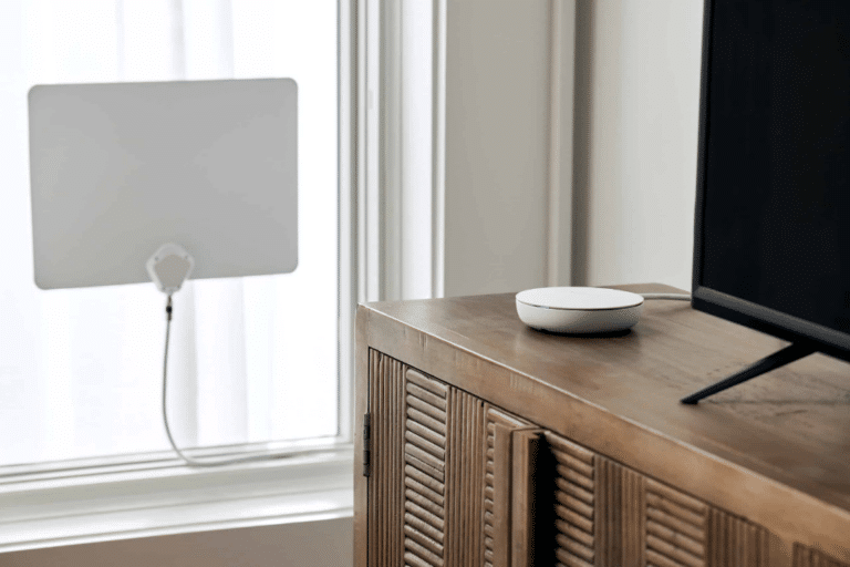 A white flat antenna in a window. A 4th Generation Tablo on a shelf beside a TV.